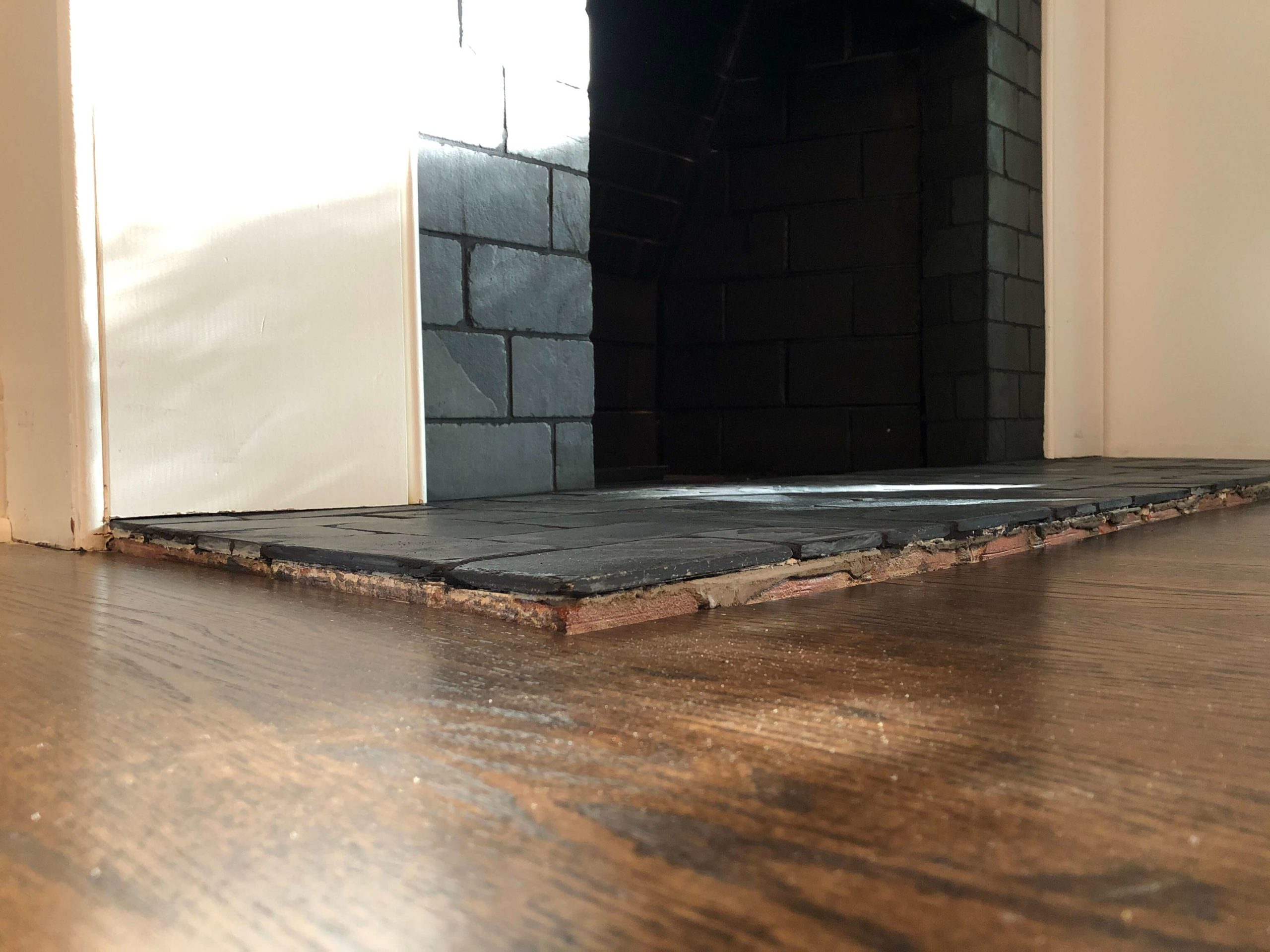 shot of the finished fireplace new slate tile is applied directly over the old pink brick Lindsey Putzier Design Studio
