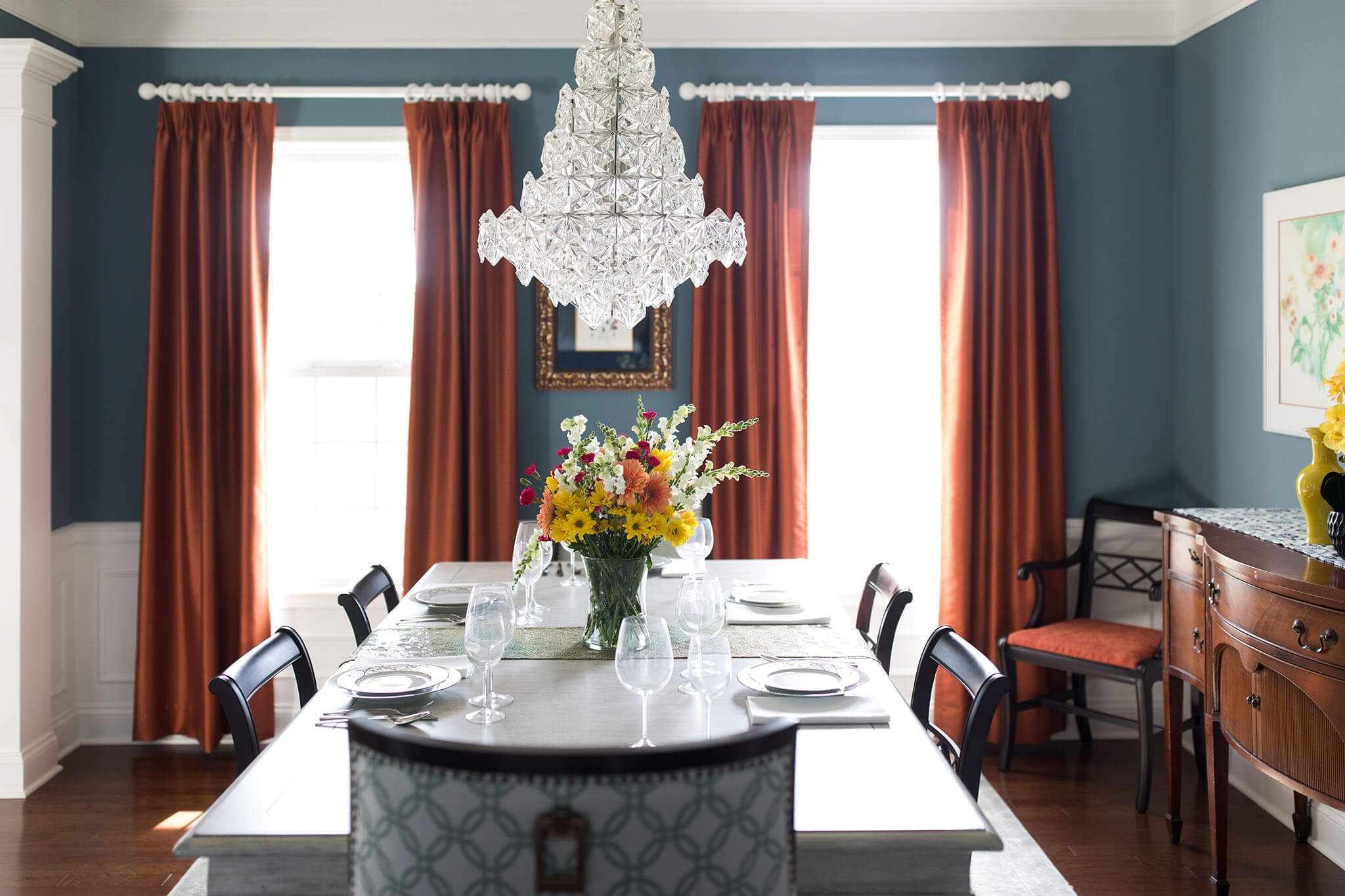 Colorful Contemporary Dining Room with Orange drapery panels contrasting blue walls Lindsey Putzier Design Studio