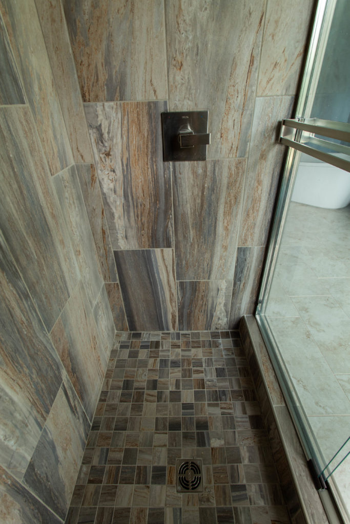 Close up of warm tones in wood like tile in Master Bathroom Shower Lindsey Putzier Design Studio