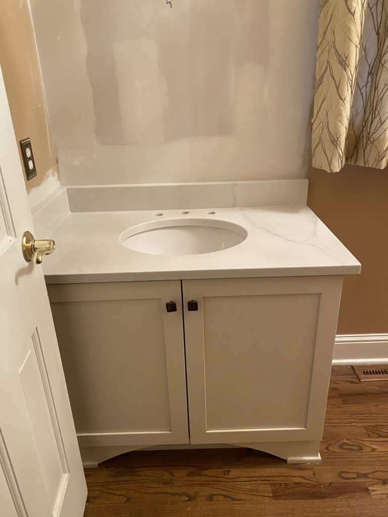 Progress photo of powder room, white undermount sink, bright quartz countertop on top vanity Lindsey Putzier Design Studio