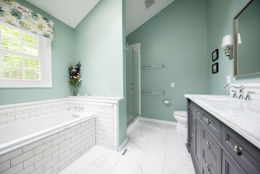 Bathroom featuring white subway tile, classic stone counters, and practical yet beautiful porcelain floors. Lindsey Putzier Design Studio