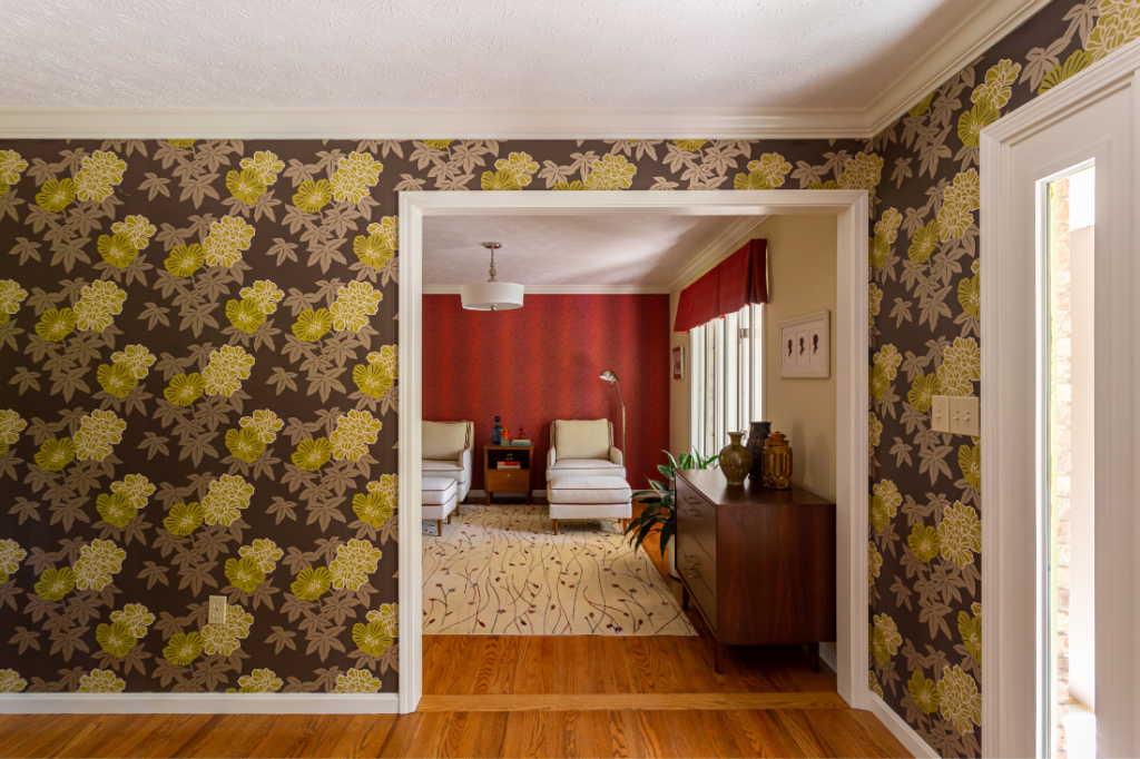 Dark floral themed wallpaper in Independence, Ohio hallway and stairway looking into Red sitting room Lindsey Putzier Design Studio