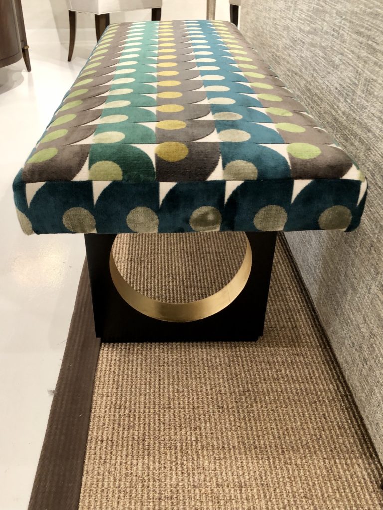 Ottoman with black legs and gilded gold accents in bright multicolored geometric patterned upholstery Lindsey Putzier Design Studio