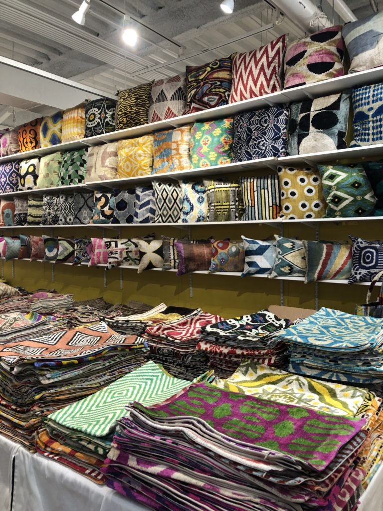 Shelves filled with many pillows and a table covered with fabrics Lindsey Putzier Design Studio