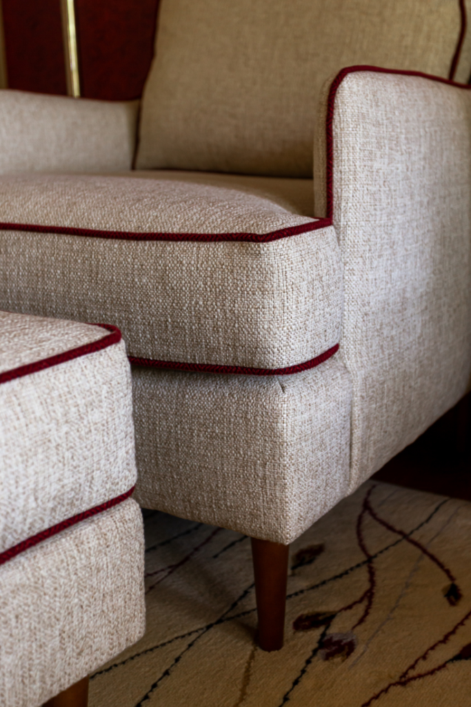 Custom neutral fabric upholstered chair and ottoman with red welt Lindsey Putzier Design Studio