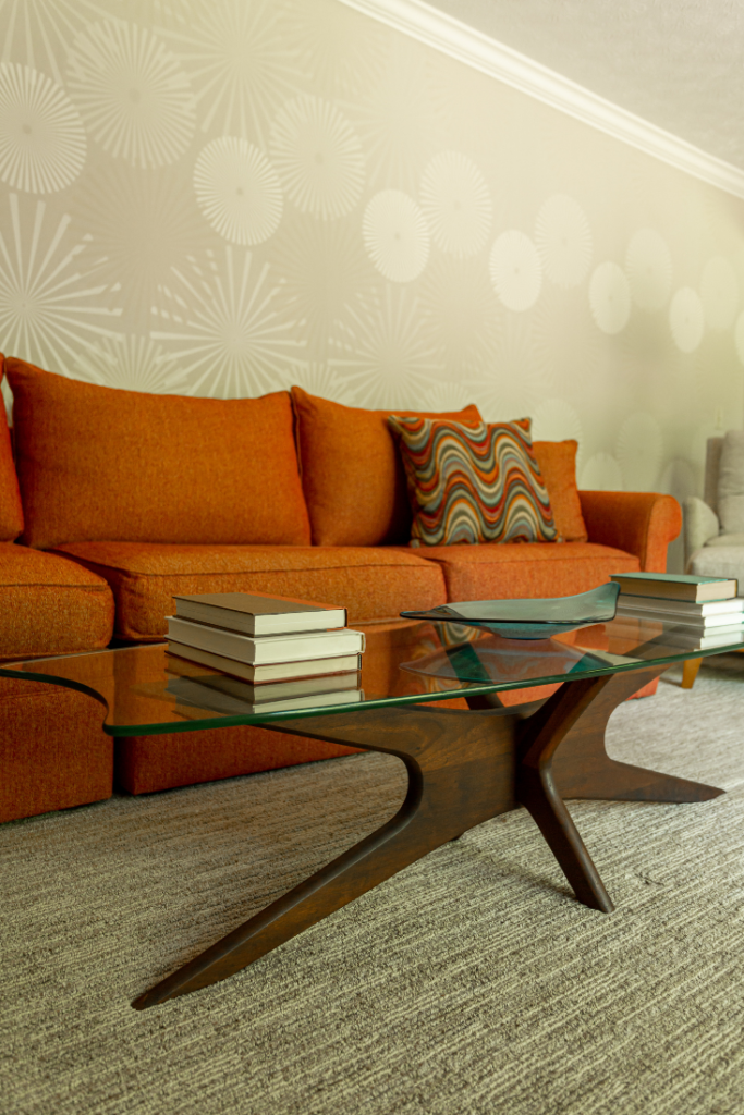 Orange Sectional with custom pillow and wooden base coffee table with glass top Lindsey Putzier Design Studio