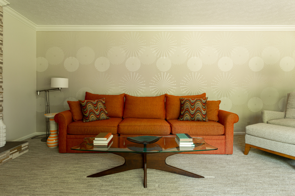 Orange sectional with glass boomerang coffee table Lindsey Putzier Design Studio