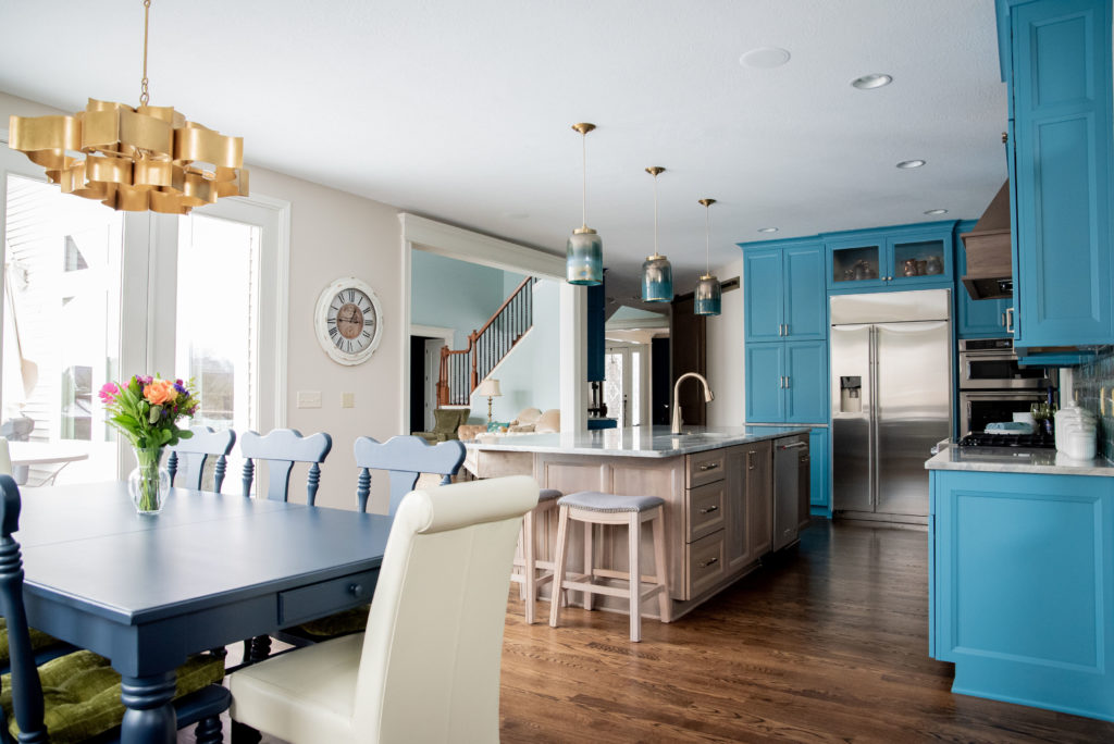 Kitchen in teal cabinets next to dinette with golden chandelier Lindsey Putzier Design Studio