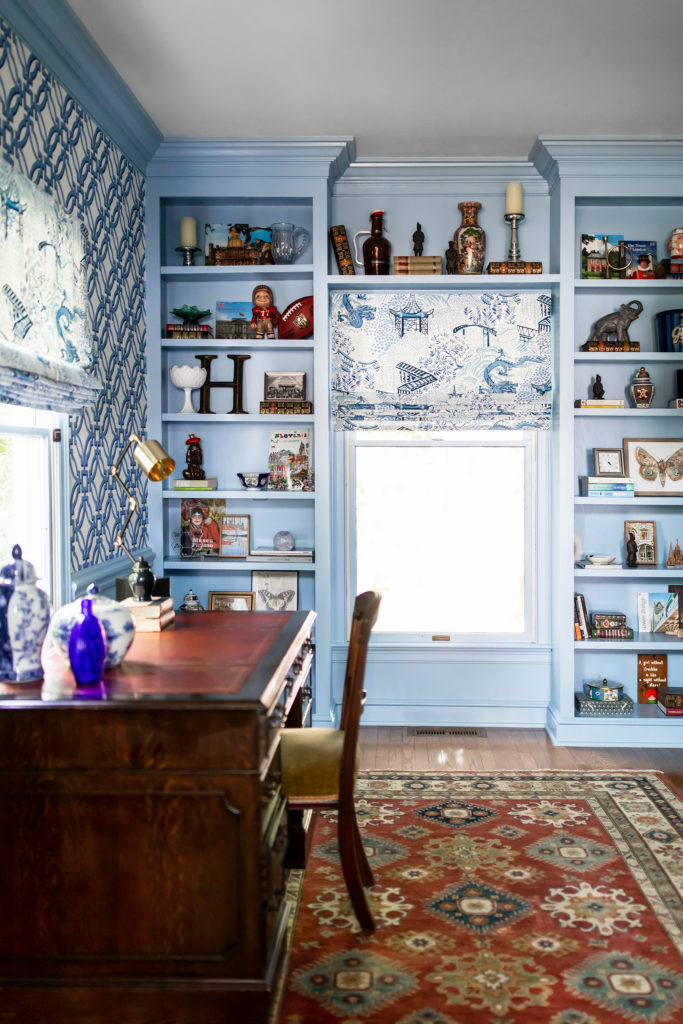 Blue office built in cabinets filled with a colorful variety of decor accessories Lindsey Putzier Design Studio