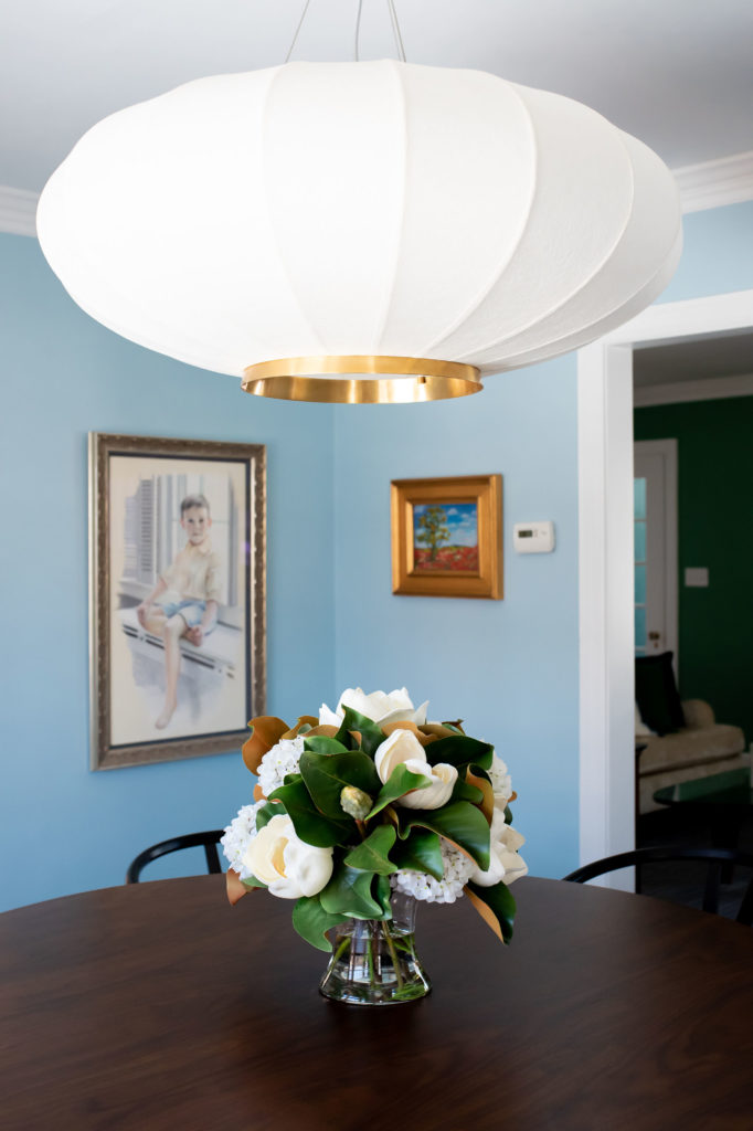 Round, white chandelier centered above round wooden dining room table Lindsey Putzier Design Studio